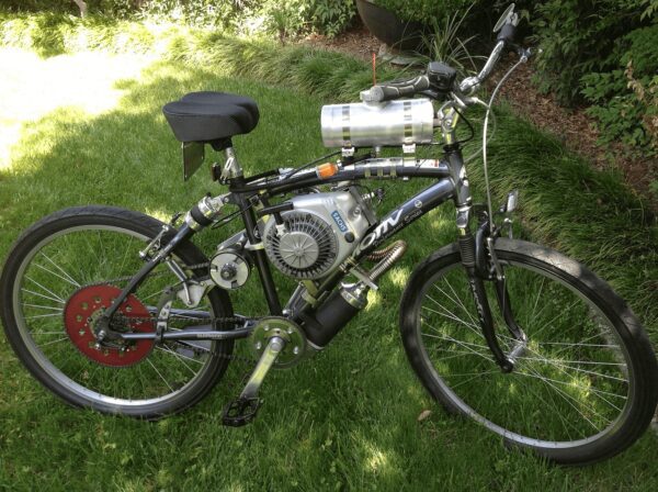 A bicycle with a motor attached to it is parked in the grass.