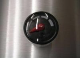 A black and red thermometer on the side of a wall.
