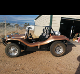 A brown and black dune buggy parked in the dirt.