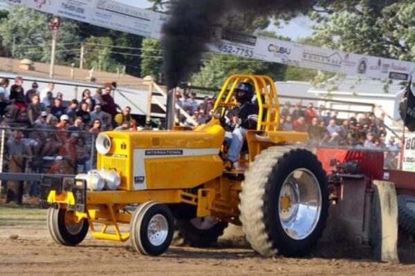 A yellow tractor is pulling a black smoke trail.