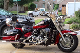 A red and black motorcycle parked in front of some houses.