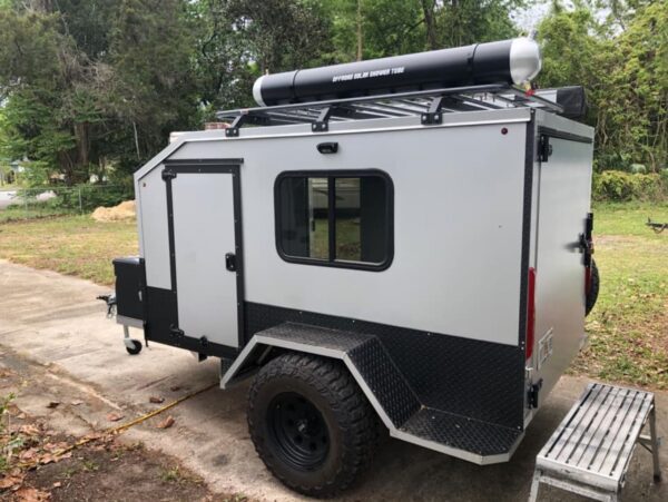 A small trailer with a large window and a pipe on the side.